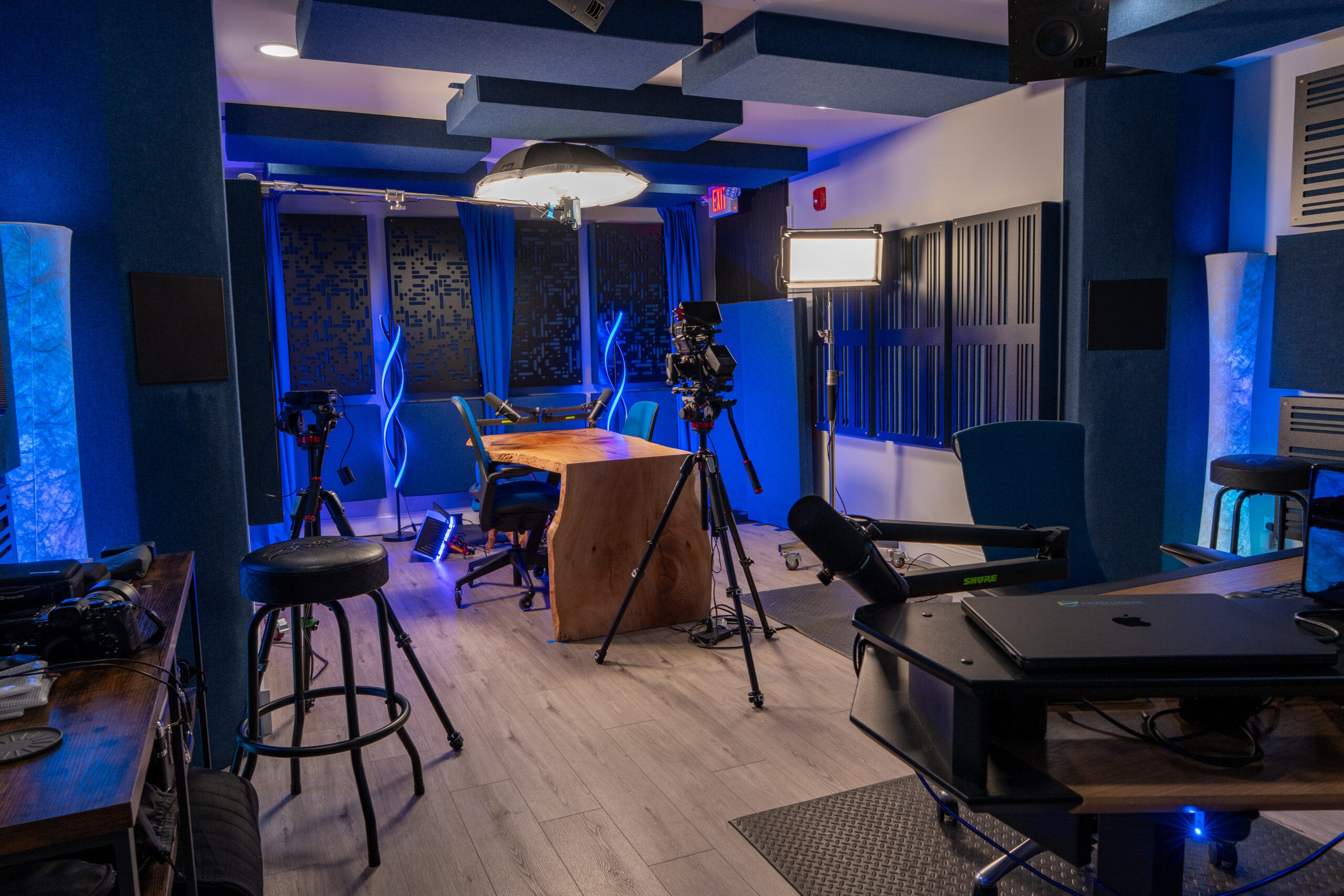 IndigoCorvid video production studio wide view with camera rig, desk, microphones, lights, and acoustic panels
